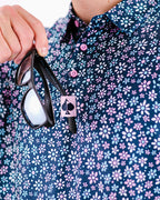 Men’s Daisy Daze golf polo by Pins & Aces featuring an all-over pink, blue, and white daisy floral print on a navy background with an athletic performance fit.