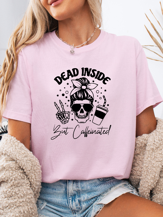Dead Inside But Caffeinated graphic available as a tee, crewneck, or sweatshirt featuring a fun coffee-inspired design on soft cotton-blend fabric, perfect for Halloween, spooky season, and everyday fall outfits. TShirt in Light Pink