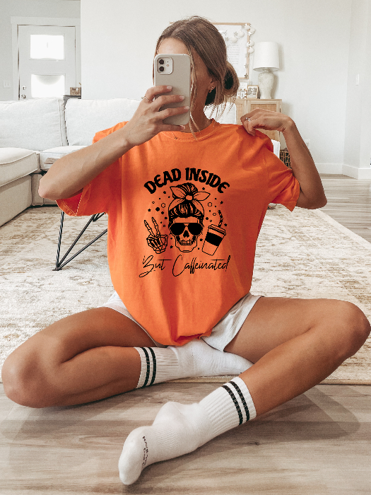 Dead Inside But Caffeinated graphic available as a tee, crewneck, or sweatshirt featuring a fun coffee-inspired design on soft cotton-blend fabric, perfect for Halloween, spooky season, and everyday fall outfits. TShirt in Orange