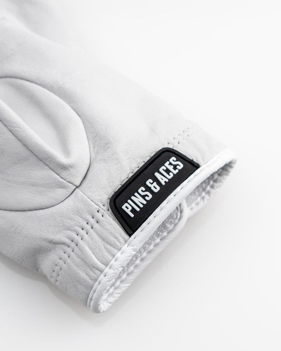 Pins & Aces Premium Tour Ghost White unisex golf glove made from 100% premium AAA Cabretta leather with moisture-wicking wrist lining and men’s standard sizing.