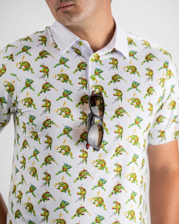White TMNT Cowabunga Classic 8-Bit golf polo by Pins & Aces featuring an all-over retro pixel-style Teenage Mutant Ninja Turtles character print.