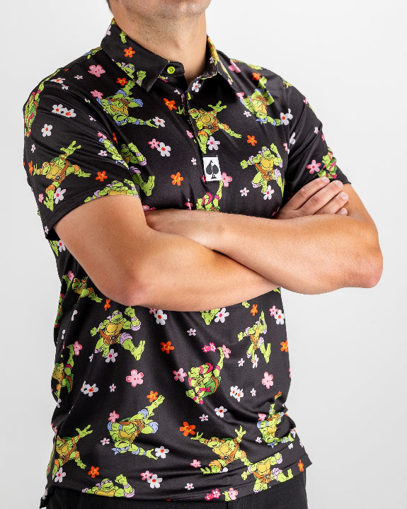 Black TMNT Turtle Flower Power golf polo by Pins & Aces featuring colorful Teenage Mutant Ninja Turtles characters and floral print.