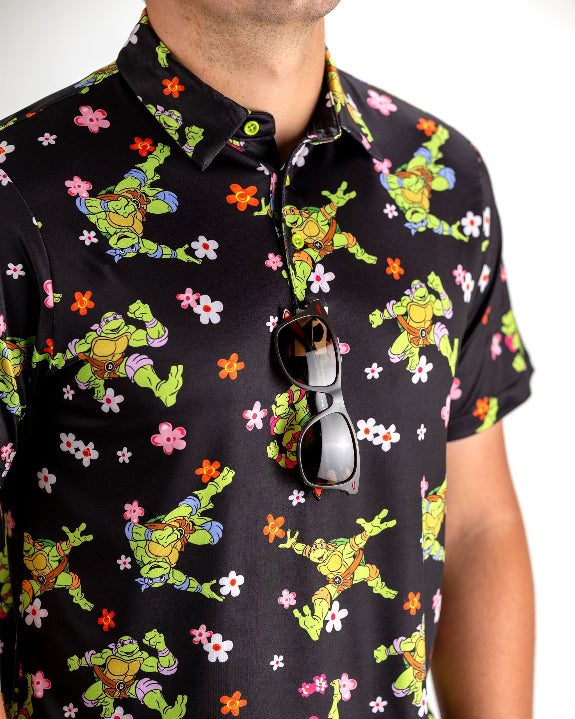 Black TMNT Turtle Flower Power golf polo by Pins & Aces featuring colorful Teenage Mutant Ninja Turtles characters and floral print.