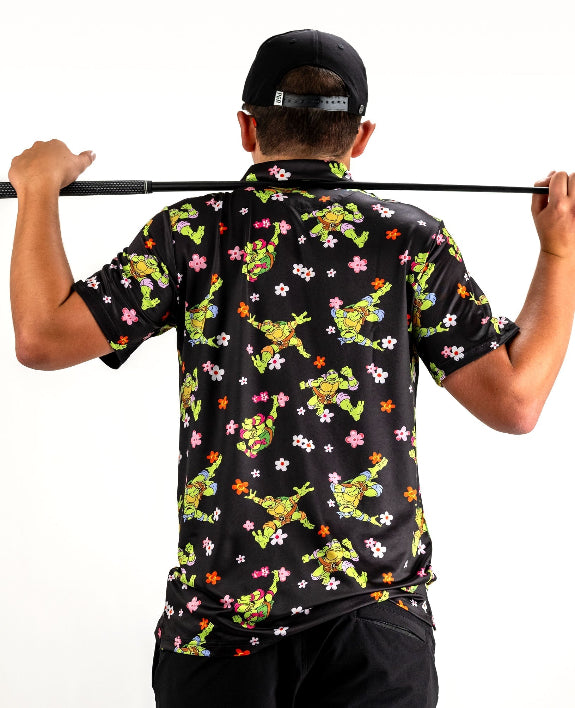 Black TMNT Turtle Flower Power golf polo by Pins & Aces featuring colorful Teenage Mutant Ninja Turtles characters and floral print.