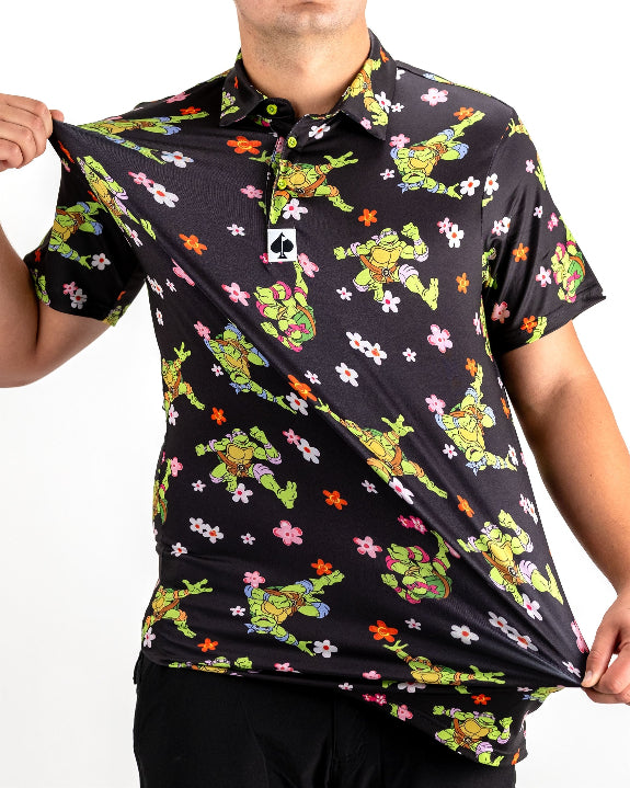 Black TMNT Turtle Flower Power golf polo by Pins & Aces featuring colorful Teenage Mutant Ninja Turtles characters and floral print.