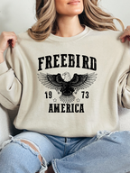 Women’s Freebird 1973 graphic tee featuring a bold Freebird America design, bald eagle graphic, black detailing, and vintage-inspired artwork on a Comfort Colors® cotton Crewneck in Ivory