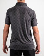 Men’s Big Blind golf polo by Pins & Aces featuring a subtle dark gray and black geometric pattern with short sleeves, collared neckline, and athletic fit.