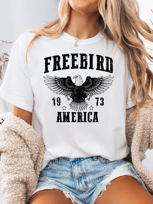 Women’s Freebird 1973 graphic tee featuring a bold Freebird America design, bald eagle graphic, black detailing, and vintage-inspired artwork on a Comfort Colors® cotton T-shirt in White