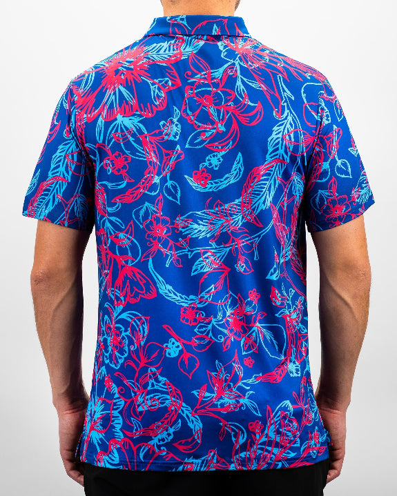 Men’s Cabo Colada golf polo by Pins & Aces featuring a vibrant coral red and aqua tropical floral print on a rich blue background with short sleeves and an athletic performance fit.