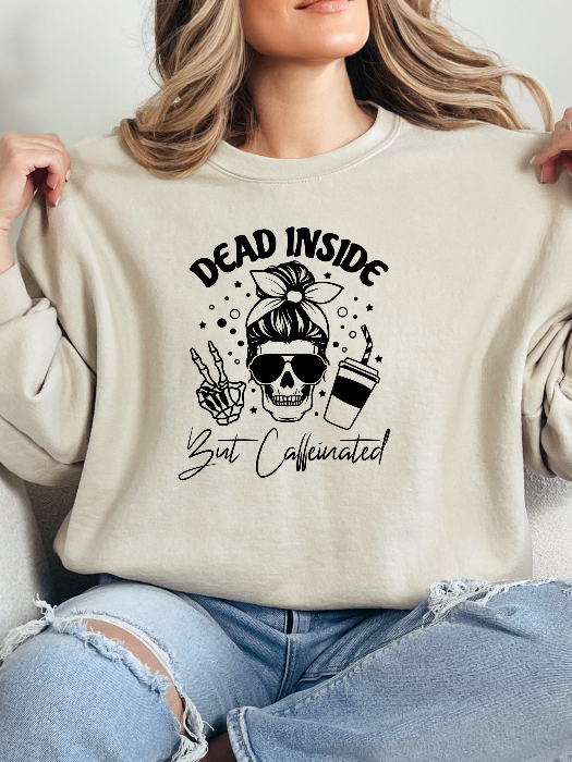 Dead Inside But Caffeinated graphic available as a tee, crewneck, or sweatshirt featuring a fun coffee-inspired design on soft cotton-blend fabric, perfect for Halloween, spooky season, and everyday fall outfits. Crewneck in Ivory