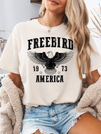 Women’s Freebird 1973 graphic tee featuring a bold Freebird America design, bald eagle graphic, black detailing, and vintage-inspired artwork on a Comfort Colors® cotton T-shirt in Ivory