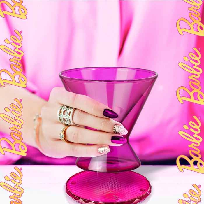 Hand holding a pink glass with 'Barbie' branding in the background