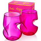 Two Barbie™ x Dragon Glassware® 16-ounce stemless wine glasses in pink and magenta with sculptural curved sides, displayed in front of a bright pink Barbie™ gift box.