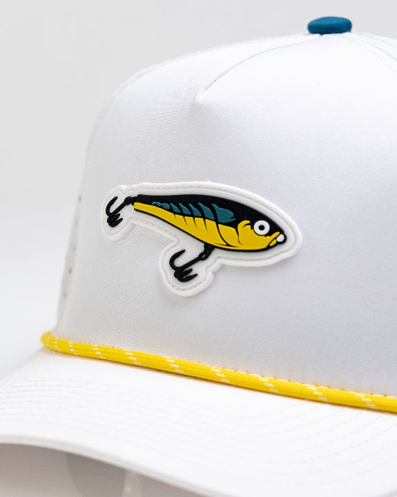 White Pins & Aces Fishing Lure perforated rope golf hat with fishing-inspired design, adjustable snapback, magnetic ball marker holder, and matching golf ball marker.