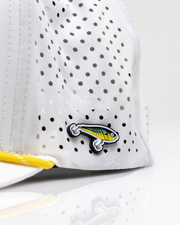White Pins & Aces Fishing Lure perforated rope golf hat with fishing-inspired design, adjustable snapback, magnetic ball marker holder, and matching golf ball marker.