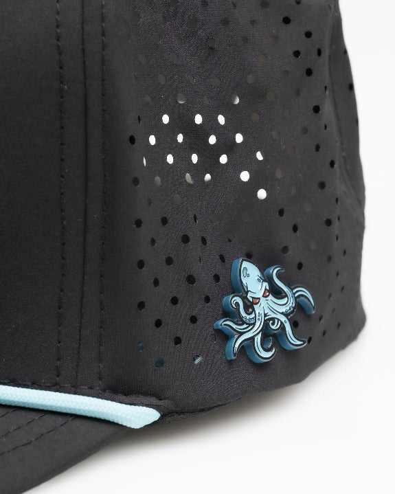 Kraken Black perforated rope golf hat by Pins & Aces featuring an all-black design, braided rope accent, breathable perforated panels, adjustable snapback, and built-in magnetic golf ball marker holder.