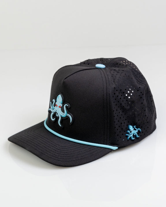 Kraken Black perforated rope golf hat by Pins & Aces featuring an all-black design, braided rope accent, breathable perforated panels, adjustable snapback, and built-in magnetic golf ball marker holder.