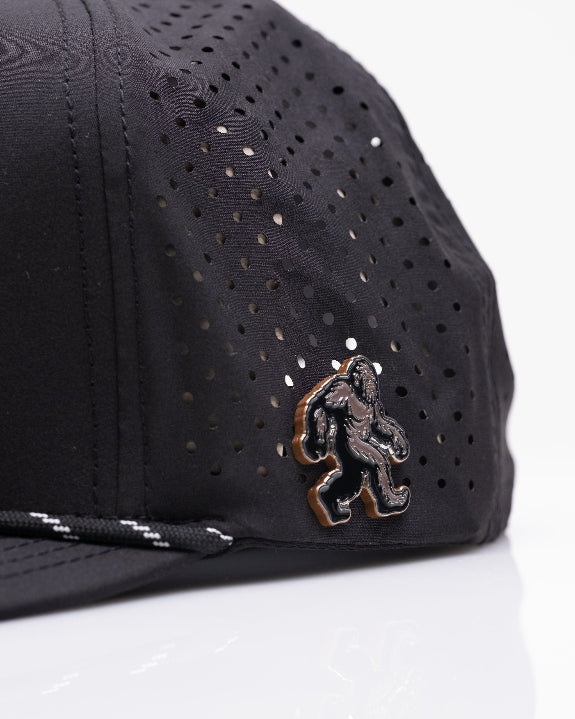 Pins & Aces Sasquatch Black perforated golf rope hat with adjustable snapback, magnetic ball marker holder, and matching golf ball marker.