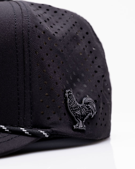Black Pins & Aces perforated rope golf hat featuring an embroidered rooster on the front, breathable side panels, rope detail, and adjustable snapback design.