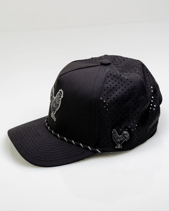 Black Pins & Aces perforated rope golf hat featuring an embroidered rooster on the front, breathable side panels, rope detail, and adjustable snapback design.