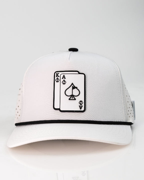 Ace/King White perforated rope golf hat by Pins & Aces with an adjustable snapback, built-in magnetic ball marker holder, and matching golf ball marker.