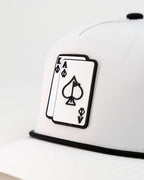 Ace/King White perforated rope golf hat by Pins & Aces with an adjustable snapback, built-in magnetic ball marker holder, and matching golf ball marker.