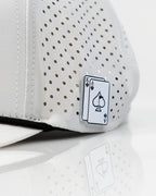 Ace/King White perforated rope golf hat by Pins & Aces with an adjustable snapback, built-in magnetic ball marker holder, and matching golf ball marker.