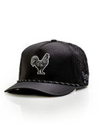 Black Pins & Aces perforated rope golf hat featuring an embroidered rooster on the front, breathable side panels, rope detail, and adjustable snapback design.