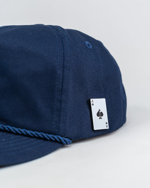 Heritage Navy rope golf hat by Pins & Aces featuring a low-profile 5-panel design, rope accent, adjustable snapback, and built-in magnetic golf ball marker holder.