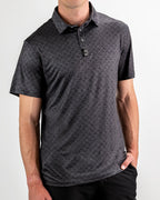 Men’s Big Blind golf polo by Pins & Aces featuring a subtle dark gray and black geometric pattern with short sleeves, collared neckline, and athletic fit.