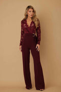 Women’s lace crochet long sleeve jumpsuit featuring sheer mesh detailing, a plunging V-neckline, adjustable D-ring waist belt, and flared legs.