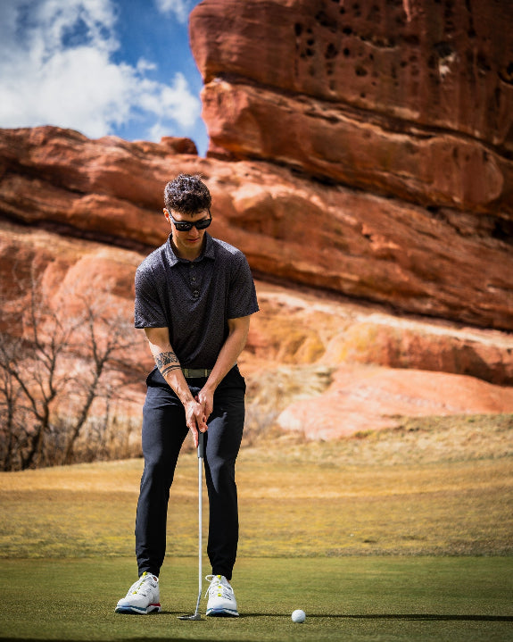 Men’s Big Blind golf polo by Pins & Aces featuring a subtle dark gray and black geometric pattern with short sleeves, collared neckline, and athletic fit.