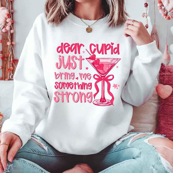 Dear Cupid Something Strong Valentine’s Day crewneck sweatshirt featuring a funny Cupid-inspired graphic on a cozy relaxed-fit unisex sweatshirt in White