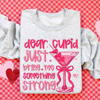 Dear Cupid Something Strong Valentine’s Day crewneck sweatshirt featuring a funny Cupid-inspired graphic on a cozy relaxed-fit unisex sweatshirt in Ash