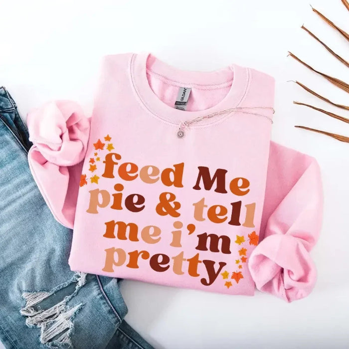 Feed Me Pie and Tell Me I’m Pretty funny Thanksgiving sweatshirt featuring a fall pie lover graphic on a cozy unisex crewneck in Light Pink