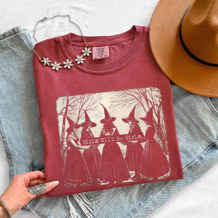 Girls Will Be Girls Comfort Colors graphic T-shirt with a playful Halloween-inspired design for spooky season in Crimson