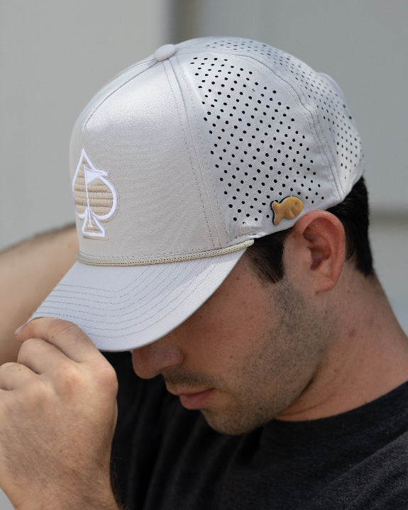 Bone off-white perforated rope golf hat by Pins & Aces featuring breathable perforated panels, braided rope detail, adjustable snapback, and built-in magnetic golf ball marker holder.