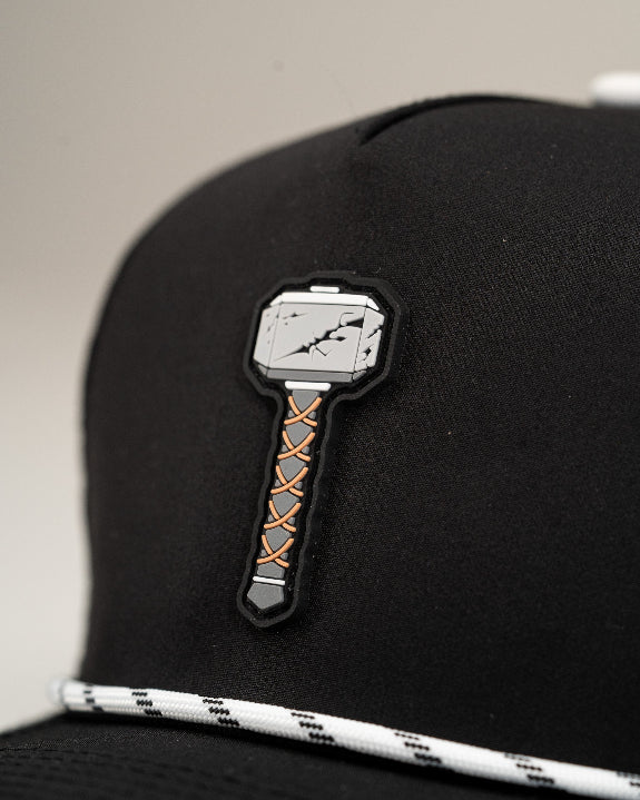 Thor’s Hammer Black perforated rope golf hat by Pins & Aces featuring a hammer-inspired design, adjustable snapback, breathable perforations, and built-in magnetic ball marker holder.