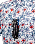 Men’s Hibiscus Harmony golf polo by Pins & Aces featuring blue and coral hibiscus flowers on a white lightweight performance golf shirt.