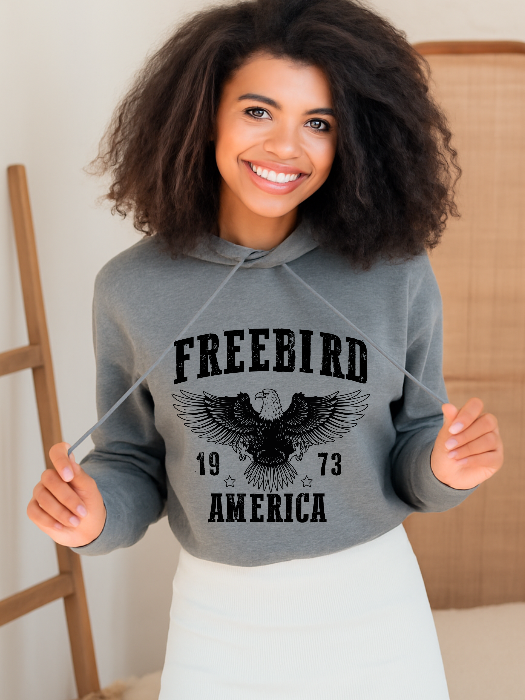 Women’s Freebird 1973 graphic tee featuring a bold Freebird America design, bald eagle graphic, black detailing, and vintage-inspired artwork on a Comfort Colors® cotton Cropped Hoodie in Grey