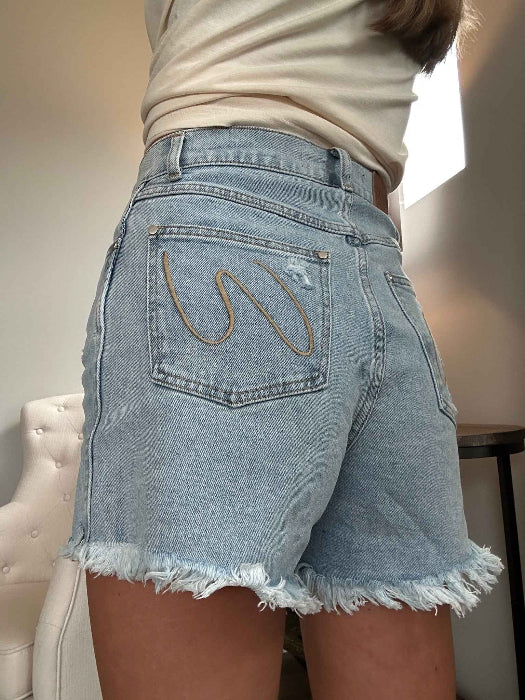 Brooke High Waisted Denim Shorts featuring a flattering high-rise waist, premium stretch denim, subtle distressed details, classic five-pocket styling, and a frayed hem for an effortless boutique summer look. Comes in a Light Wash