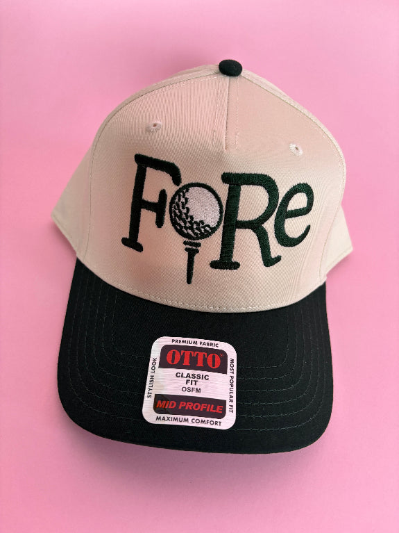 FORE women’s golf trucker hat featuring bold FORE lettering, a breathable mesh back, curved bill, and adjustable snapback closure.