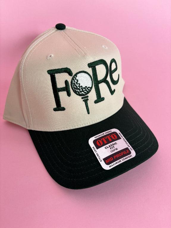 FORE women’s golf trucker hat featuring bold FORE lettering, a breathable mesh back, curved bill, and adjustable snapback closure.