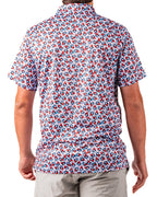 Men’s Bomb Pop Splatter golf polo by Pins & Aces featuring an all-over red, white, and blue splatter pattern with short sleeves and an athletic performance fit.