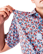 Men’s Bomb Pop Splatter golf polo by Pins & Aces featuring an all-over red, white, and blue splatter pattern with short sleeves and an athletic performance fit.