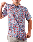 Men’s Bomb Pop Splatter golf polo by Pins & Aces featuring an all-over red, white, and blue splatter pattern with short sleeves and an athletic performance fit.