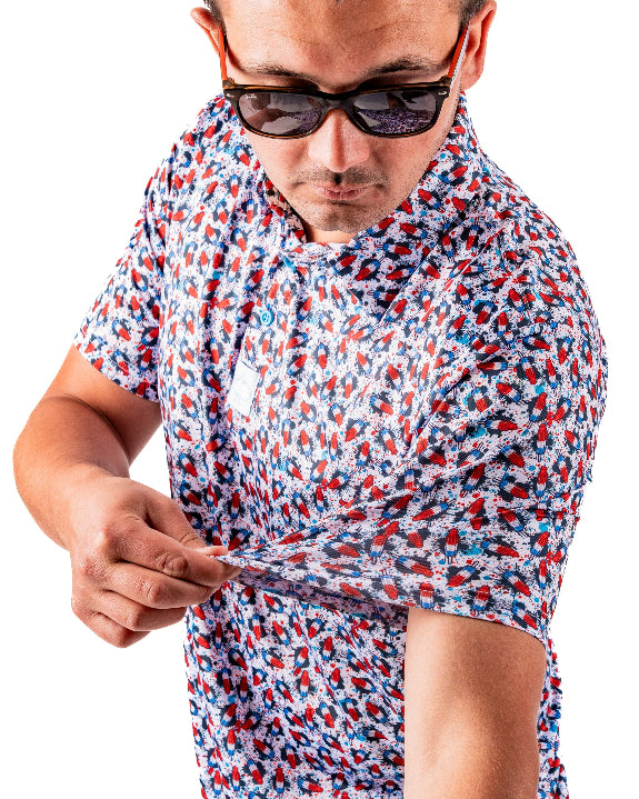 Men’s Bomb Pop Splatter golf polo by Pins & Aces featuring an all-over red, white, and blue splatter pattern with short sleeves and an athletic performance fit.
