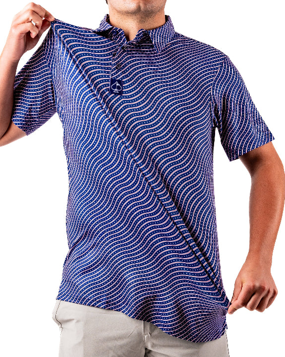 Men’s Wavy Stars & Stripes golf polo by Pins & Aces featuring a navy, red, and white wavy patriotic pattern with short sleeves and an athletic performance fit.