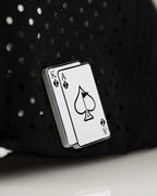 Ace/King Black perforated rope golf hat by Pins & Aces featuring a black poker-inspired design, braided rope accent, adjustable snapback, and built-in magnetic ball marker holder.
