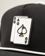 Ace/King Black perforated rope golf hat by Pins & Aces featuring a black poker-inspired design, braided rope accent, adjustable snapback, and built-in magnetic ball marker holder.